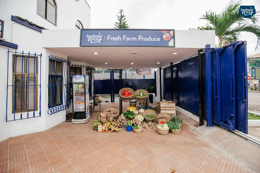 The Fresh Farm Produce entrance with baskets of tomatoes, peppers, plantain and greens laid out front