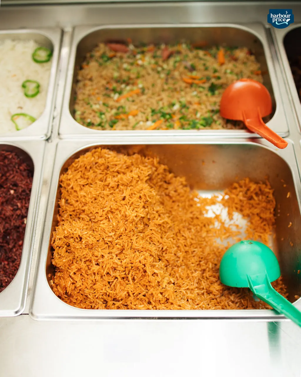 Steam trays of jollof rice and vegetable fried rice at the counter