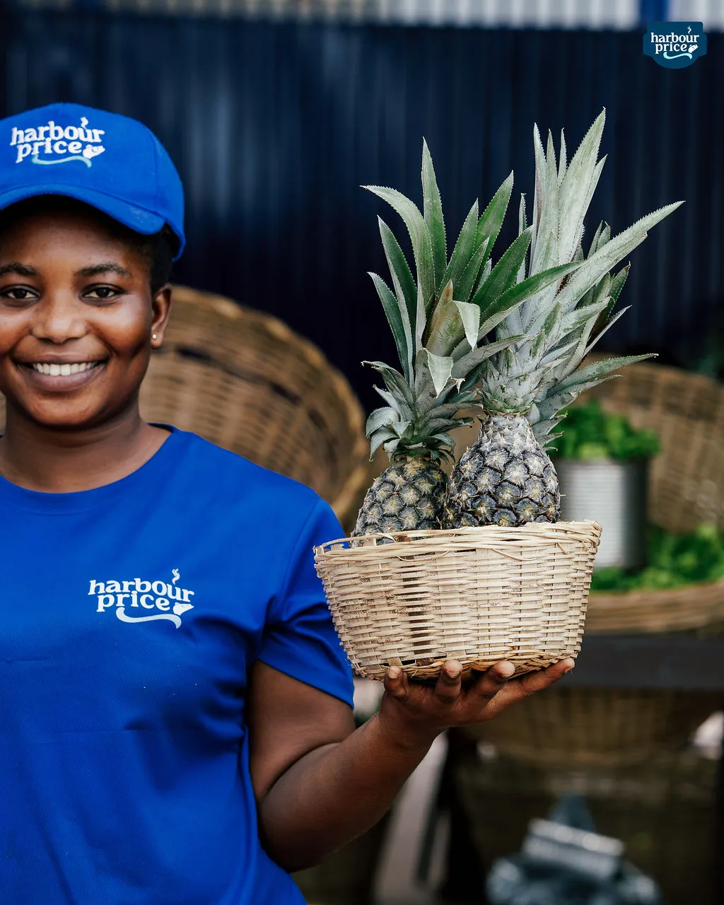 A smiling Harbour Price staffer holds a basket of pineapples at the farm market
